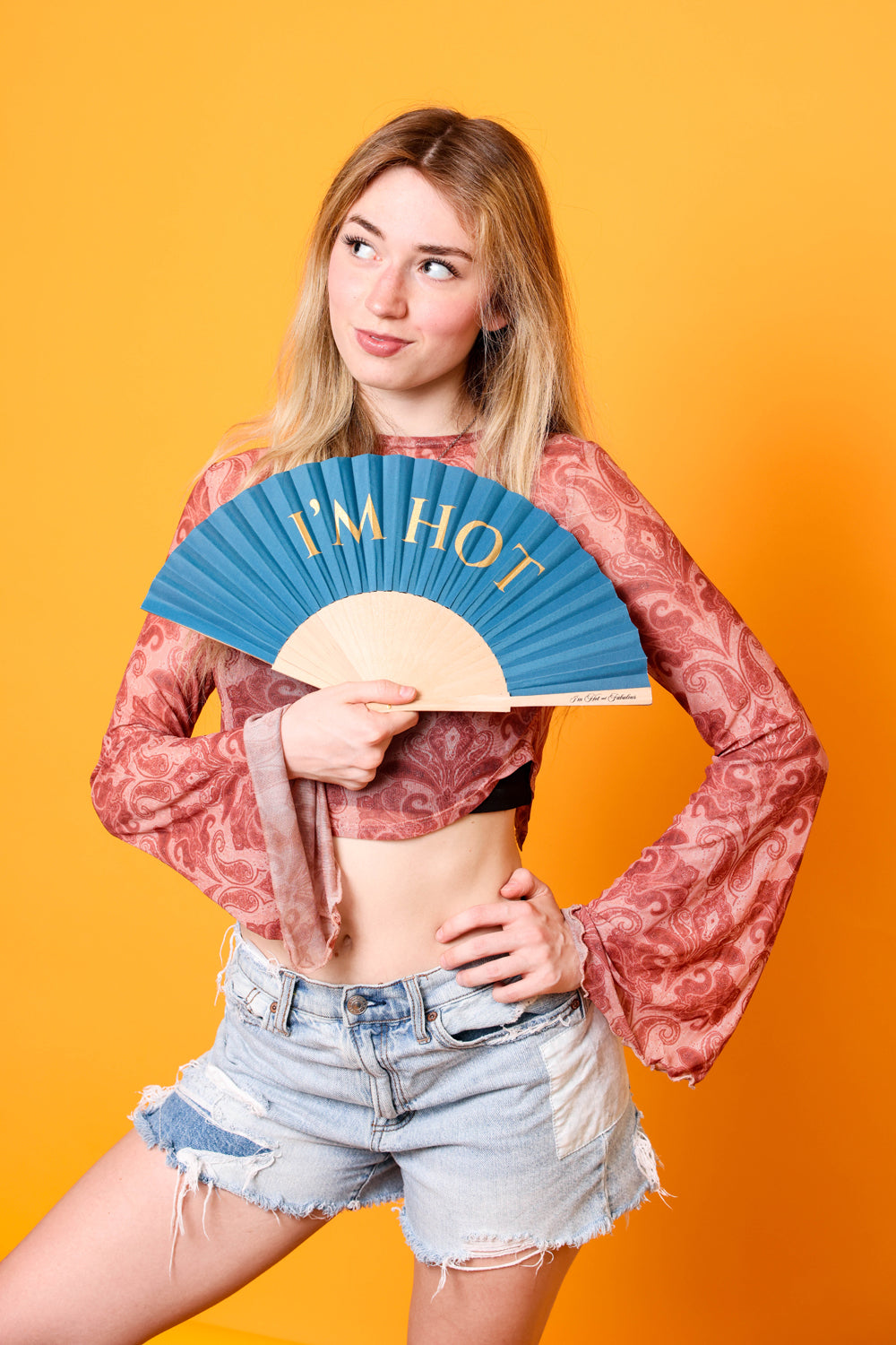 Woman holding a fan with 'I'm Hot' text against an orange background