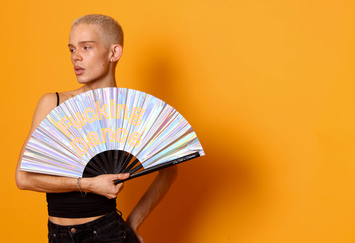 Person holding a colorful fan with text against an orange background