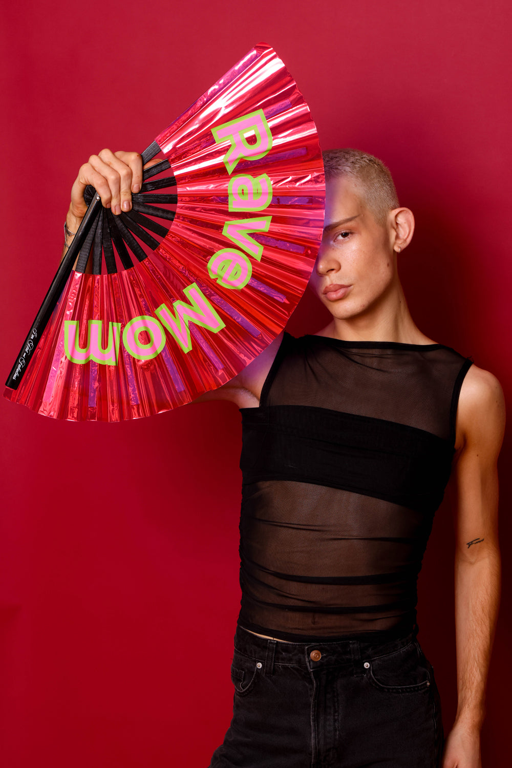 Person holding a pink fan with 'Rave Mom' text against a red background