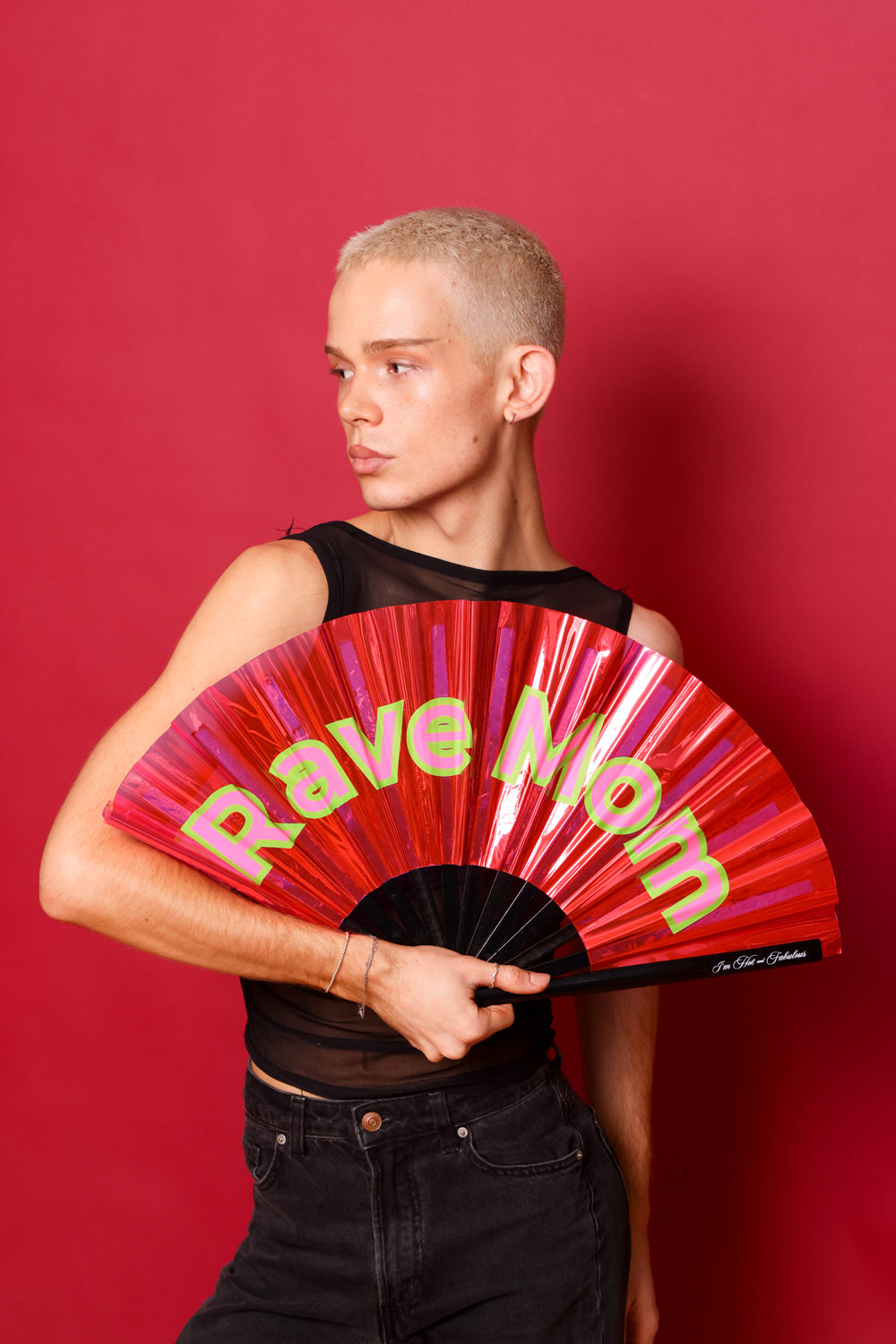 Person holding a pink  fan with 'Rave Mom' text against a red background