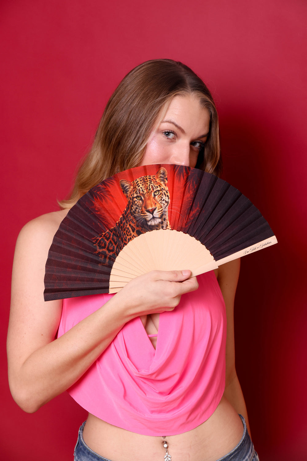 Woman holding a fan with a tiger design against a red background