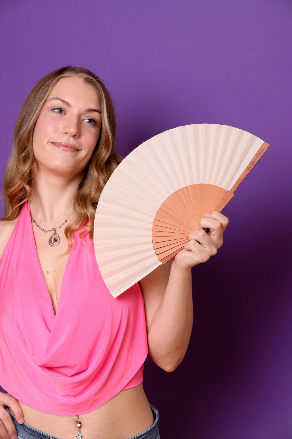 Woman holding an ivory fan against a purple background