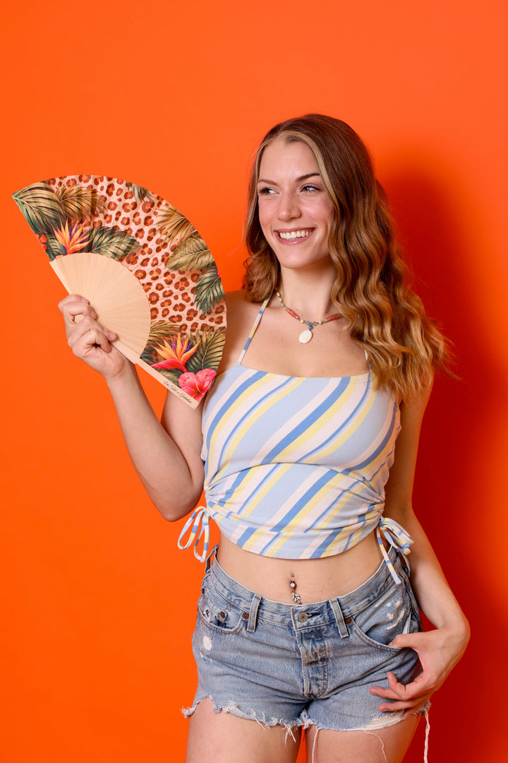 Woman holding a decorative fan against an orange background