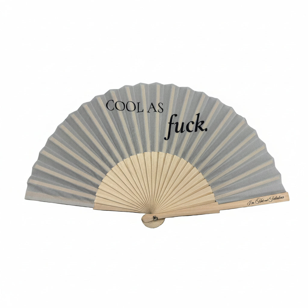 Handheld fan with text Cool As Fuck on a gray surface