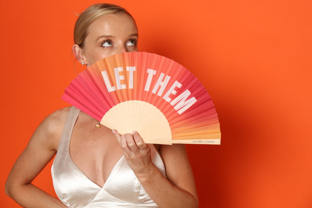 Woman holding Let Them Hand Fan