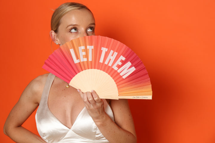 Woman holding Let Them Hand Fan