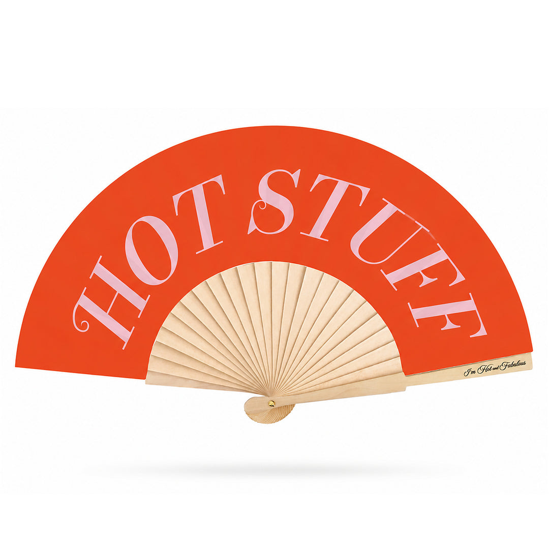 A folding hand fan with a bright orange-red curved upper section and natural wood ribs, featuring the words 'HOT STUFF' in large white serif letters.
