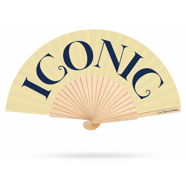 A folding hand fan with a cream-colored canopy and natural wood ribs, featuring the word 'ICONIC' printed in large navy blue letters across the top.