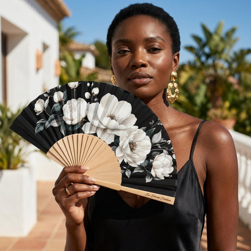 Woman holding a floral fan outdoors with plants and a building in the background